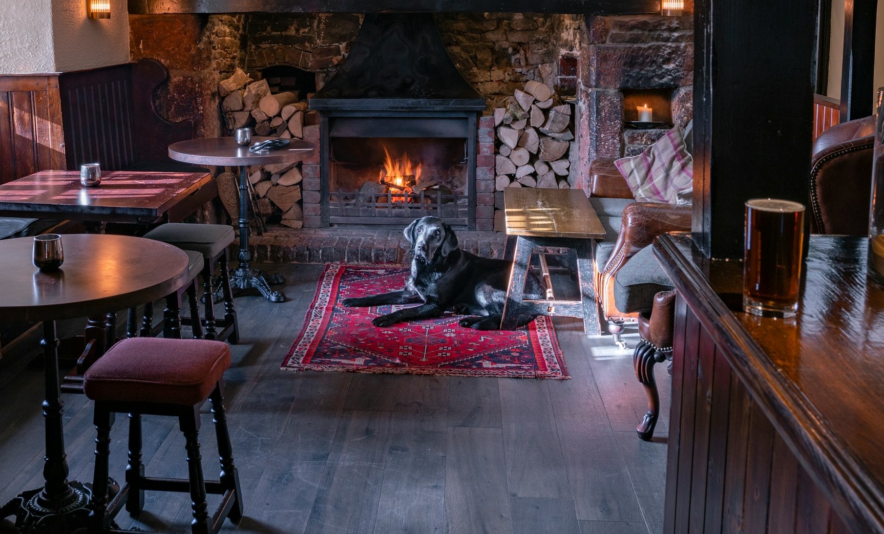 A dog sitting in front of pub fireplace